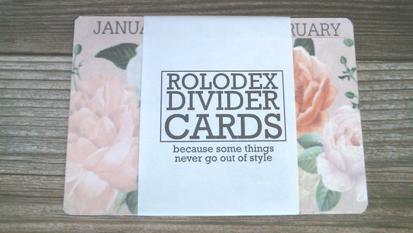 3 inch by 5 inch Rolodex dividers in a shabby rose print. They are in delicate shades of pink and coral with green leaves. The tabs have the months of the year on them. They are wrapped with a wrapper that says "Rolodex Divider Cards - because some things never go out of style".