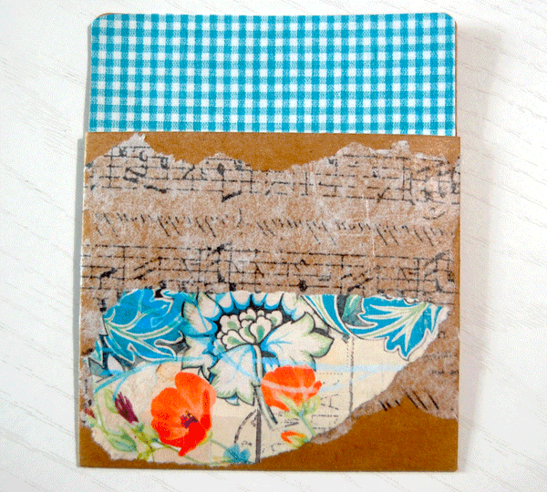 A kraft paper library pocket that is decorated with the large floral print, the blue gingham check, and the black and white print printed on tissue paper.