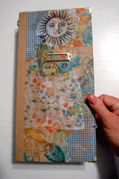 A hand made junk journal. The cover has a gold metal label plate and gold metal corner protectors.
