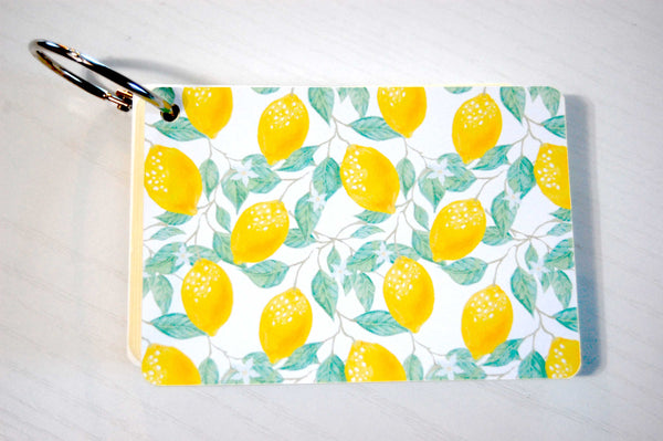 Internet password Keeper on a silver ring. The cover is a pretty lemon print with green leaves and white flowers.
