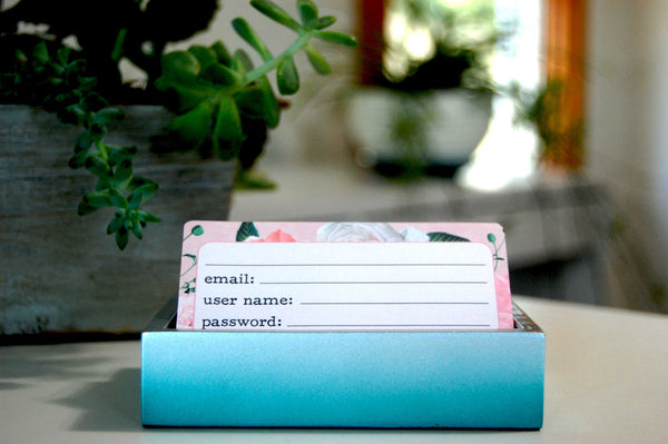 Pretty floral Rolodex Password Cards in a holder with plants in the background.
