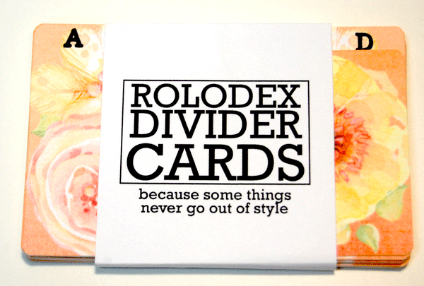 A wrapped bundle of 13 Alphabetized Watercolor Floral Rolodex Dividers. They are a colorful print of coral, yellow and pink flowers with green leaves and have a black and white wrapper. The wrapper says " ROLODEX DIVIDER CARDS: because some things never go out of style."
