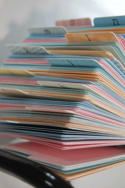 A close up of a Rolodex filled with colorful hand made Rolodex dividers and cards in pastel colors.