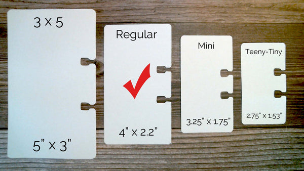 Four white rectangular Rolodex card sizes displayed on a wood surface, labeled 3 x 5 inches, Regular 4 x 2.2 inches, Mini 3.25 x 1.75, and Teeny-Tiny 2.75 x 1.53. The regular size is checked.
