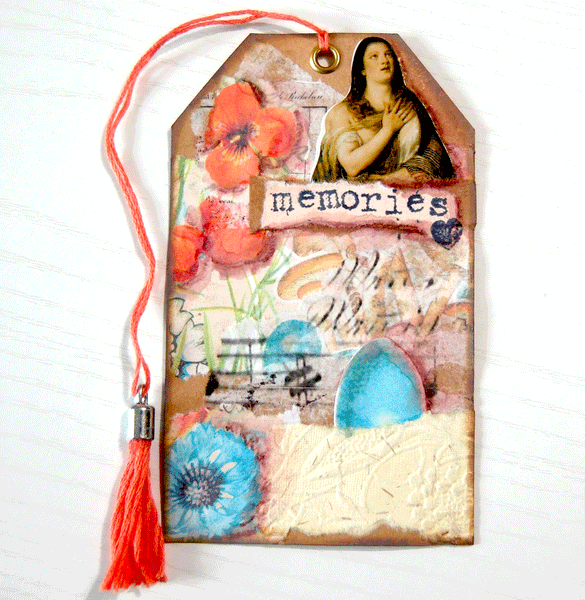 A decorated kraft cardstock tag. It is collaged with floral paper in teal and orange. There is also an egg sticker, a sticker of a woman, embossed paper, and the word "memories" stamped on old paper. There is an orange tassel through the gold grommet at the top of the tag.