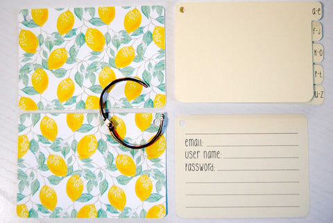 Flat lay display of all of the elements of the lemon password keeper: Front and back cover,  silver ring, 5 yellow dividers, and 40 yellow password cards