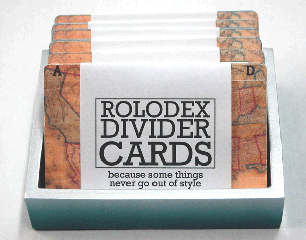 Vintage Map Rolodex Dividers. They are wrapped in a bundle of 13. The wrapper is white with black writing that says, "ROLODEX DIVIDER CARDS: because some things never go out of style" The dividers are in a holder. There are many packs of matching Rolodex password cards behind them.