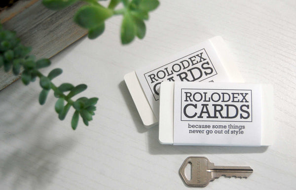 Two wrapped bundles of mini Rolodex cards with a key for size comparison. The wrapper says, "ROLODEX CARDS: because some things never go out of style." There is a succulent plant in the background.