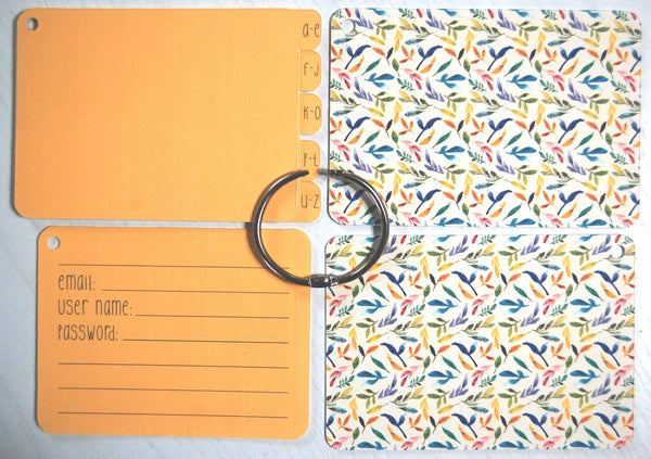 Flat lay display of all of the elements of the Watercolor Garden password keeper: Front and back cover, silver ring, 5 orange dividers, and 40 orange password cards