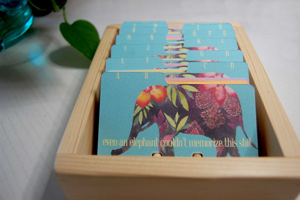 Teal Rolodex dividers with a colorfully patterned elephant on them. They are in a wooden holder with coordinating Rolodex cards in pink, orange, green and blue.