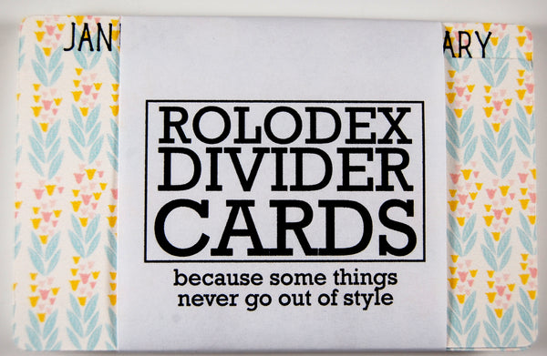 Rolodex Divider Refills: A pack of 13 Rolodex dividers with the months of the year on the tab (and a blank). The dividers are white with a pretty colored pattern: pastel blue leaves and tan and pink tulip flowers. They are wrapped in a wrapper that says: "ROLODEX DIVIDER CARDS" because some things never go out of style."